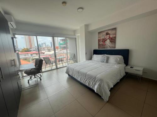 a bedroom with a bed and a balcony with a table at Blue Dream in San Francisco in Panama City