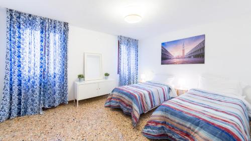 a bedroom with two beds and blue curtains at Silk Road in Venice