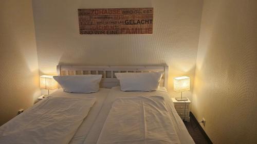 a bedroom with a bed with two pillows and two lamps at Strandhotel - Budget in Hohwacht