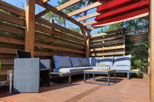 une pergola en bois avec un canapé et une table dans l'établissement Maison des Bonheurs Océaniques - Welkeys, à Capbreton