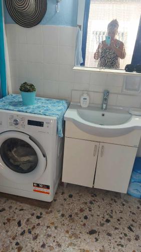 a woman taking a picture of a washing machine and a sink at Villa by the Sea, Nyfida Lesvos in Nifida
