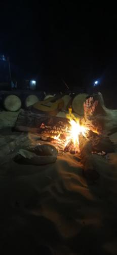 a fire on the beach at night at Les jardins fleuris de lompoul sur mer in Tioukougne Peul