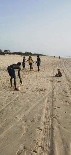 a group of people playing in the sand on the beach at Les jardins fleuris de lompoul sur mer in Tioukougne Peul
