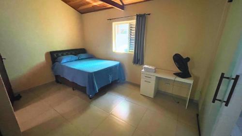 a bedroom with a bed and a desk and a window at Casa Temporada - Centro Guararema SP in Guararema