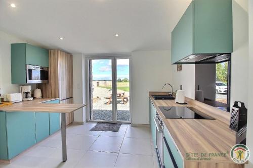 une cuisine avec des placards verts et une vue sur l'océan dans l'établissement Gîte Louise entre Erquy et Fréhel 2 chambres, à Plurien