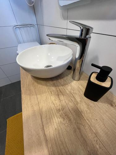 a bathroom with a white bowl sink on a wooden floor at Bella Apartment Ostrava in Ostrava