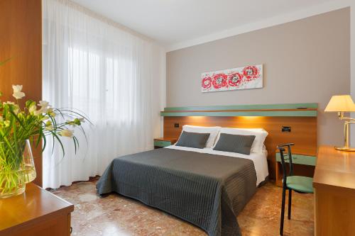 - une chambre avec un lit et un vase de fleurs dans l'établissement Hotel Europeo, à Sottomarina