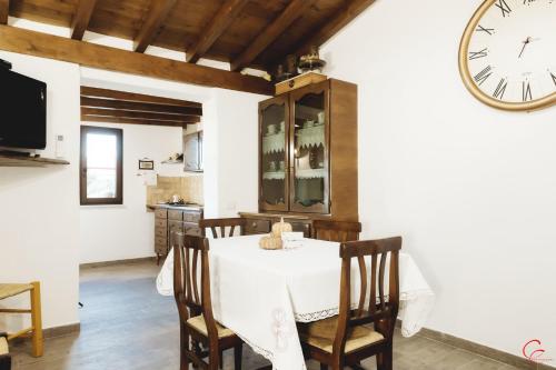 a dining room with a table and a clock on the wall at S'Arrosa de Monti in Villaputzu