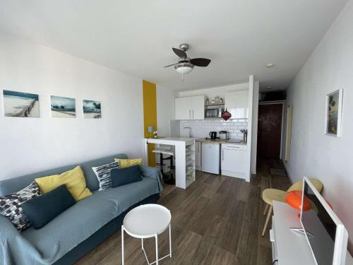 un salon avec un canapé bleu et une cuisine dans l'établissement Studio agréable - Le Lavandou - FR-1-308-81, au Lavandou