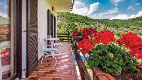a balcony with red flowers and a table and chairs at Apartment Gina in Opatija