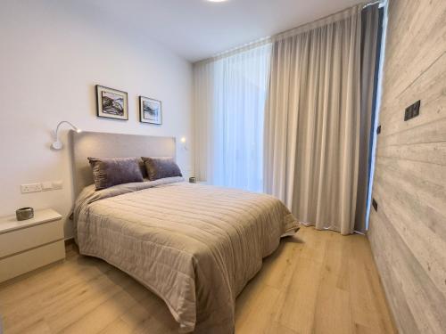 a bedroom with a bed and a large window at Malberry Park 301 - Modern 2bedroom Apt with Shared Heated Pool, Sauna, Gym, Jacuzzi in Paphos City