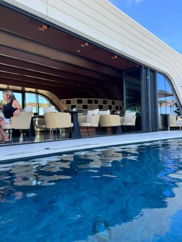 a woman sitting in chairs next to a swimming pool at Sea view Mercury Tower, Rooftop infinity Pool in St. Julianʼs