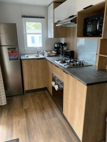 une cuisine avec un évier et une cuisinière four supérieur dans l'établissement Mobilhome au bassin d'Arcachon, à Lège-Cap-Ferret