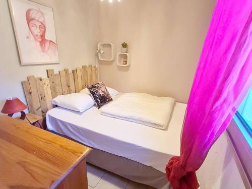 Cette petite chambre comprend un lit avec des rideaux roses. dans l'établissement T2 avec Piscine et Tennis - Parking - 250 m de la plage - FR-1-316-288, à Six-Fours-les-Plages