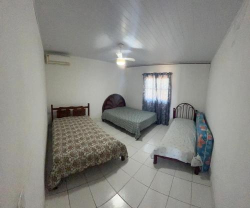 Un dormitorio con dos camas y una silla y una ventana. en Milagres, en São Miguel dos Milagres