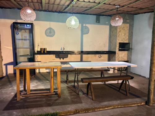 una mesa y bancos en una habitación con luces colgantes en Milagres, en São Miguel dos Milagres