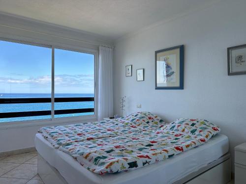 a bedroom with a bed with a view of the ocean at Beach Apartment Arguineguin in Arguineguín