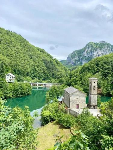an old building in a river with mountains in the background at Cozy House in Castelnuovo di Garfagnana + Large Garden in Castelnuovo di Garfagnana