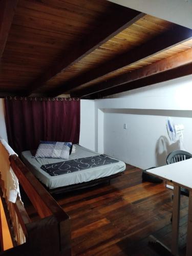a bed in a room with a wooden floor at Sobrado São Chico, Ubatuba SFS in São Francisco do Sul
