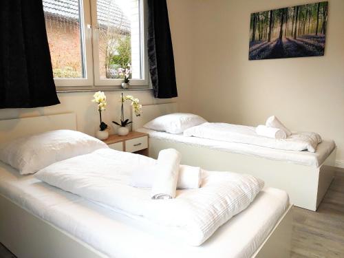 two beds with white sheets in a room with a window at Aparthotel Dat Witte Hus Apartment for 6 guests with 3 rooms in Geesthacht