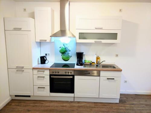 a kitchen with white cabinets and a stove top oven at Aparthotel Dat Witte Hus Apartment for 6 guests with 3 rooms in Geesthacht
