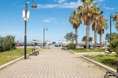 a sidewalk with palm trees and a street light at Casa Ludovica in Isola delle Femmine