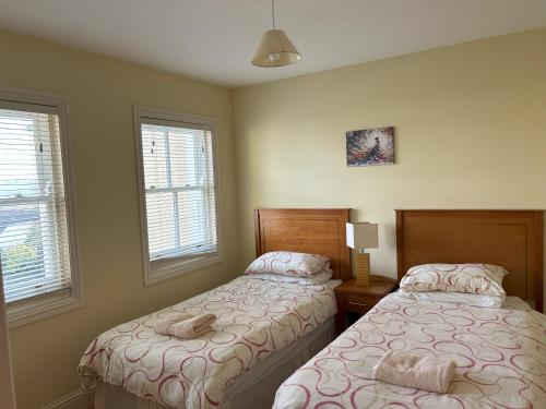 a bedroom with two beds and two windows at Number 1 Bank House in Schull