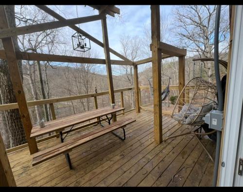 a wooden deck with a bench and a swing at Cabin in the treetops! in Lancaster