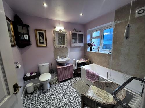 a bathroom with a tub and a toilet and a sink at Glastonbury Rose Cottage in Glastonbury
