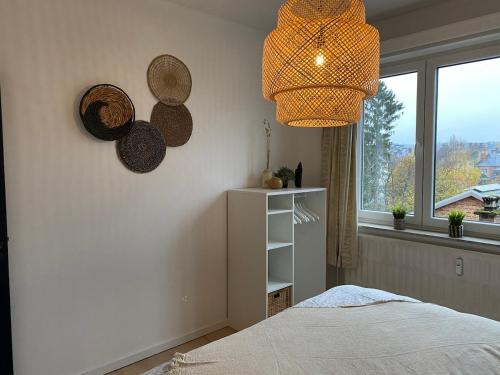 a bedroom with a bed and a window and a chandelier at Appartement lumineux, idéalement situé - Enfants bienvenus in Namur