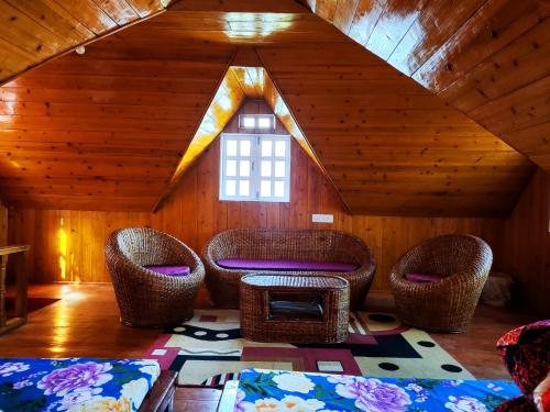 a room with wicker chairs and a table in a cabin at Solitude in the Himalayas in Darjeeling