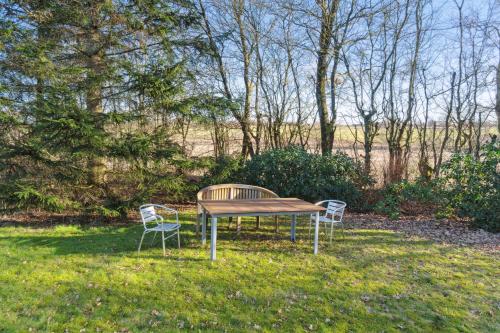 a picnic table and two chairs in the grass at Lovely Holiday Home Near Gudhjem in Gudhjem