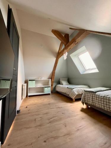 une chambre mansardée avec deux lits et une fenêtre dans l'établissement Maison de vacances à la ferme - Déconnexion en Normandie - Balnéo, à Annouville-Vilmesnil