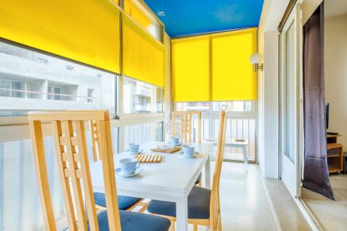 une salle à manger avec des murs jaunes et une table et des chaises blanches dans l'établissement A quelques pas de la mer, à Roquebrune-Cap-Martin