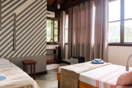 a room with two beds and two windows at Atelier Arte Paraty Mirim in Paraty