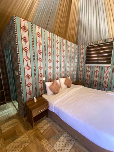 a bedroom with a bed and a wall with wallpaper at Lowrance luxury camp in Wadi Rum