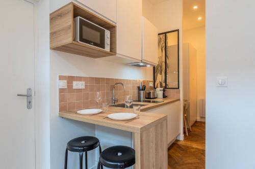 une cuisine avec un comptoir avec deux lavabos et deux tabourets dans l'établissement Grand studio fonctionnel et entièrement rénové, à Tourcoing