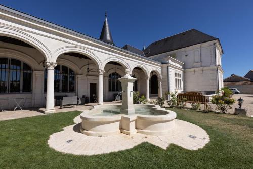 a large white building with a fountain in the yard at Château Pellisson in Cognac