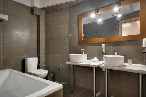 a bathroom with two sinks and a toilet and a mirror at Valtos Beach Hotel in Parga