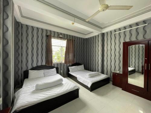 a bedroom with two beds and a mirror at Motel Thiên Phúc 1 in Can Tho