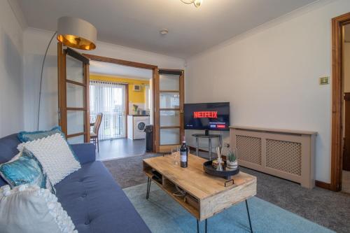 a living room with a blue couch and a table at Ideal Contractor Stay 2-Bed Near Glasgow Fort in Garthamlock