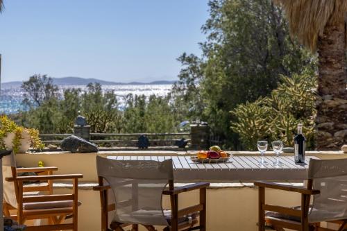a table with glasses of wine and a bowl of fruit at So close to the sea in Agios Ioannis Tinos