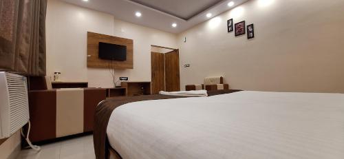 a bedroom with a large bed and a television at New Sun International & Banquet Hall in Jamshedpur