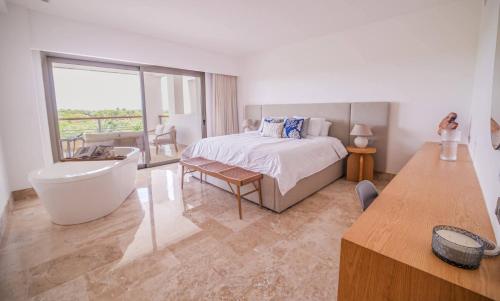 a bedroom with a bed and a tub and a sink at La Amada Residences Private Beach Getaway with Pools & Gym in Cancún
