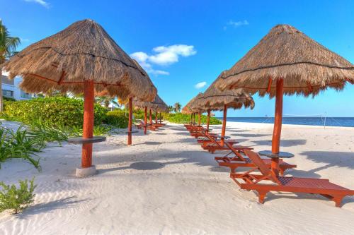 una fila de sillas y sombrillas en una playa en La Amada Residences Private Beach Getaway with Pools & Gym, en Cancún