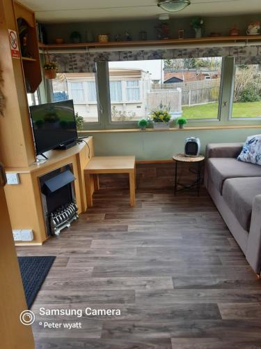 a living room with a couch and a tv at Gina's Static caravan,118 Sandsgate in Hemsby