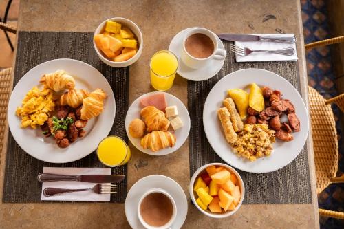 a table with plates of breakfast foods and cups of coffee at Hotel Windsor House Inn By GEH Suites in Bogotá
