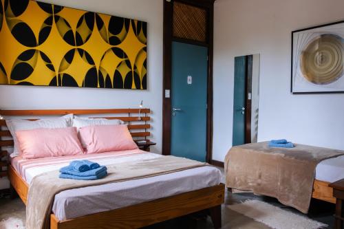 a bedroom with a bed and a painting on the wall at Atelier Arte Paraty Mirim in Paraty