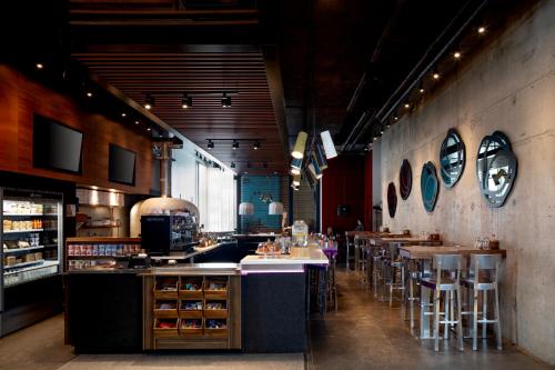 a restaurant with a bar with stools and tables at Alt Hotel Toronto Airport in Mississauga