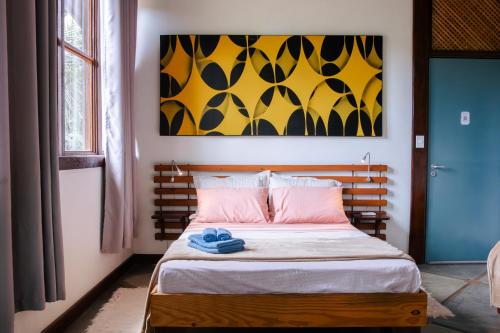 a bedroom with a bed with a painting on the wall at Atelier Arte Paraty Mirim in Paraty